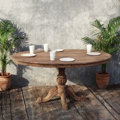 a wooden table sitting on top of a wooden floor next to potted plants