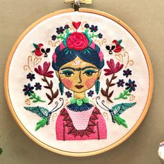 embroidered portrait of a woman with flowers in her hair on a white wall mounted hoop