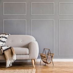 a white couch sitting in front of a gray wall next to a chair and rug