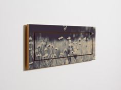 a wall mounted light switch plate with dandelions painted on it's side