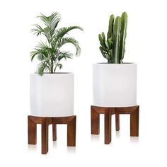 two white planters with wooden legs and plants in them, one on each side