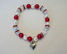 Czech druk beads in cream, red, and clear AB beads with red rhinestone rondelle accents. 7 1/2 inch stretch bracelet fits 7 to 8 inch wrist. Great for Valentine's gift or just because. Druk beads are slightly translucent with pearlized finish. Heart charm is lead free alloy. White Heart Stretch Bracelet For Valentine's Day, White Beaded Stretch Bracelet For Valentine's Day, White Stretch Bracelet With Heart Beads For Valentine's Day, Adjustable White Crystal Bracelet For Valentine's Day, White Stretch Bracelet With Heart Charm As Gift, White Adjustable Crystal Bracelet For Valentine's Day, White Charm Bracelet With Round Beads For Valentine's Day, White Crystal Bracelet With Heart Beads, White Charm Bracelet For Valentine's Day