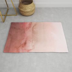 a pink and red area rug on the floor next to a basket with a plant in it