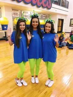 three girls in blue shirts and green leggings posing for the camera with their hands up