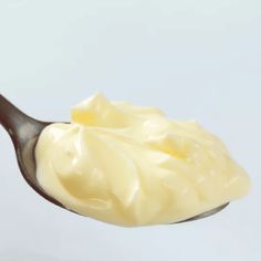 a spoon filled with cream on top of a white table