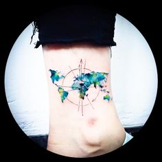 a woman's stomach with a watercolor map tattoo on her left side ribcage