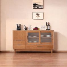 a wooden cabinet with glass doors in a living room next to a painting on the wall