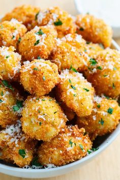 a white bowl filled with fried food covered in parmesan cheese and seasoning