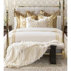 a white bed with gold pillows and blankets