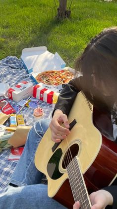 a person sitting on a blanket playing an acoustic guitar