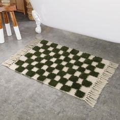 a green and white rug sitting on top of a floor next to a wooden table