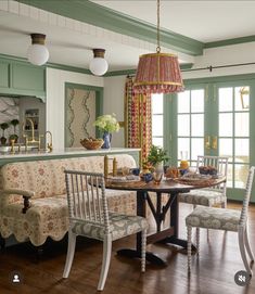 a table and chairs in a room with green walls, wood floors and wooden flooring