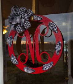 a monogrammed wreath hanging on the front door of a house with a checkered bow