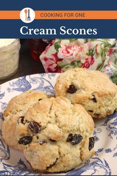 two scones on a blue and white plate next to a jar of cream sauce