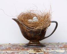 an old tea pot with some birds eggs in it