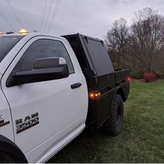 a white truck parked on top of a lush green field