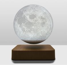 A glowing moon levitates above a wood platform Levitating Moon Lamp, Planet Lamp, Moon Table, Lamp 3d, Magnetic Levitation, Moon Lamp, 3d Printing Technology, Sand Art, Our Solar System