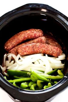 some sausages and onions in a slow cooker with green beans on the side