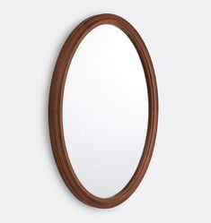 an oval mirror on the wall with a wooden frame and brown wood trim around it