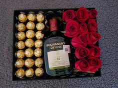 a bottle of booze, chocolates and roses in a box on the floor