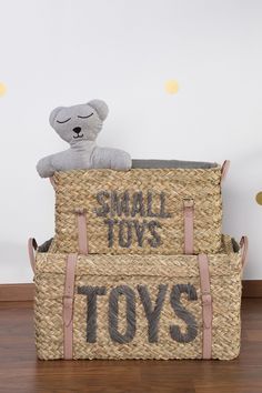 a stuffed toy bear sitting on top of two baskets with toys written on the sides