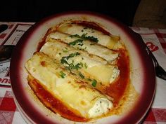 some food is sitting on a red and white plate with a checkered table cloth