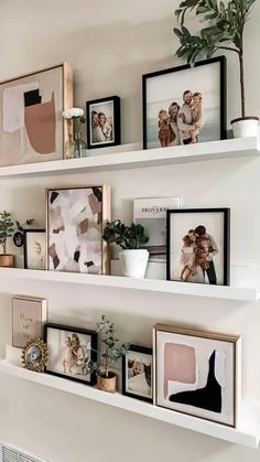 some white shelves with pictures and plants on them