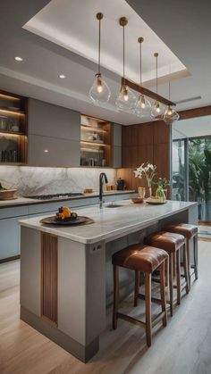 a kitchen island with stools and lights hanging from it's ceiling over the counter