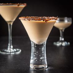 three glasses filled with dessert sitting on top of a black table next to each other