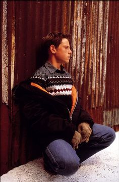 a man sitting on the ground wearing a jacket