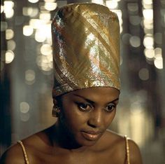 a woman wearing a gold head wrap and looking at the camera with an intense look on her face