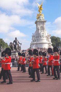 a group of men in red uniforms standing next to each other near a large statue