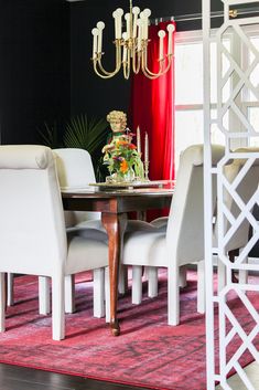 a dining room table with white chairs and a chandelier hanging from the ceiling