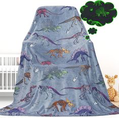 a blanket with dinosaurs on it next to a crib