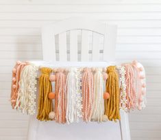 a white chair with some tassels on it and a string of beads hanging from the back