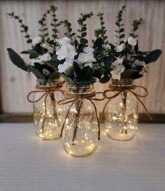 three mason jars filled with flowers and string lights