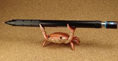 a toy crab holding a large black pen on top of it's back legs