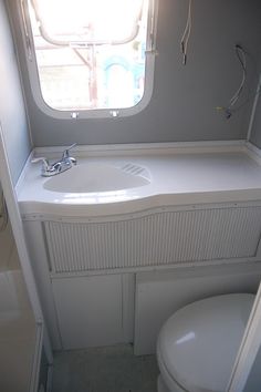 a bathroom with a toilet, sink and window