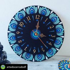 a clock that is on the wall next to a vase with flowers in it and an ornament