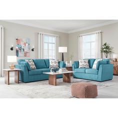 a living room filled with blue couches and pillows on top of a white rug