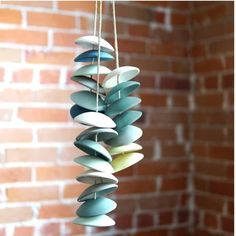 a wind chime hanging from a string in front of a brick wall with white and blue decorations