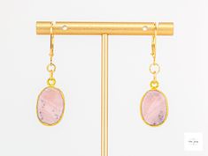 Behold these lovely gold-leafed pink Peruvian opal drop earrings! They exude understated elegance and add a modern feminine touch to your look. They are easily dressed up or down, and are perfect for any occasion. Beautiful, smooth, gold-leafed pink Peruvian opal bezels. These beautiful stones have natural patterns in shades for pink, grey, white, dusty rose pink coral pink, black and white. Gold-plated lever backs for a secure and comfortable fit. 1.75 inches longThese unique and beautiful earrings are perfect for a special gift or addition to your own collection! Due to natural variations in the gemstones your purchased item may not be identical to the one pictured. There may be natural but slight asymmetries (small differences) and imperfections in the size, shapes, colors, and patterns Single Opal Earring As A Gift, Elegant Pink Opal Jewelry With Natural Stones, Elegant Pink Opal Jewelry For Formal Occasions, Elegant Formal Pink Opal Jewelry, Elegant Gold Jewelry With Pink Opal, Elegant Pink Opal Oval Jewelry, Elegant Pink Opal Jewelry Gift, Elegant Pink Opal Jewelry For Gift, Handmade Elegant Pink Opal Jewelry