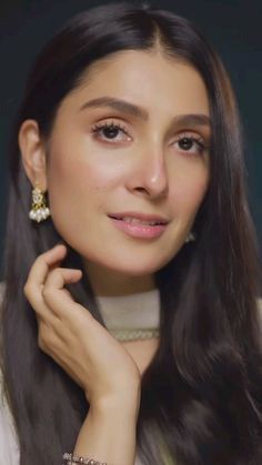 a woman with long dark hair wearing earrings