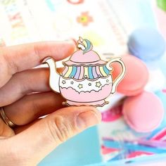 a person holding a pink teapot shaped pin