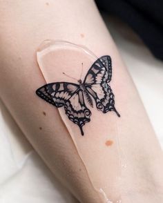 a small butterfly tattoo on the left thigh and right leg, it appears to be in black ink