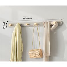 a coat rack with two coats hanging from it's hooks and a purse hanging on the wall