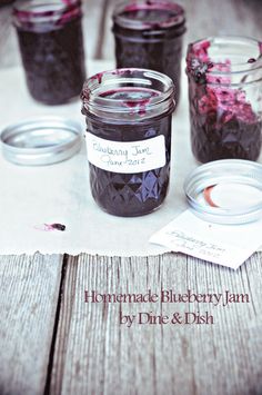 homemade blueberry jam in glass jars on a wooden table with pink and purple flowers