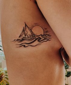 a small sailboat tattoo on the back of a man's left arm and shoulder