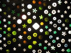 many different colored buttons on a black surface with white and green dots in the middle