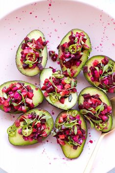 a white plate topped with sliced avocados covered in beets and radishes